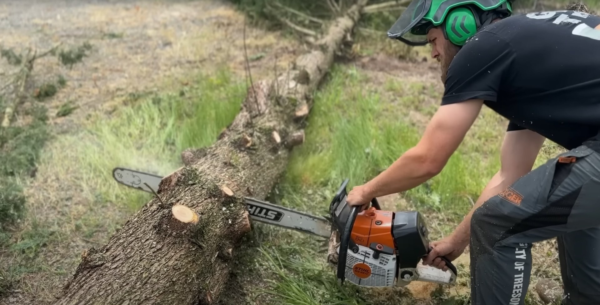 Chainsaw cutting through fallen tree trunk during emergency cleanup