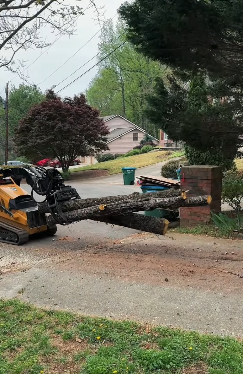 Tree removal equipment moving large tree logs in residential neighborhood